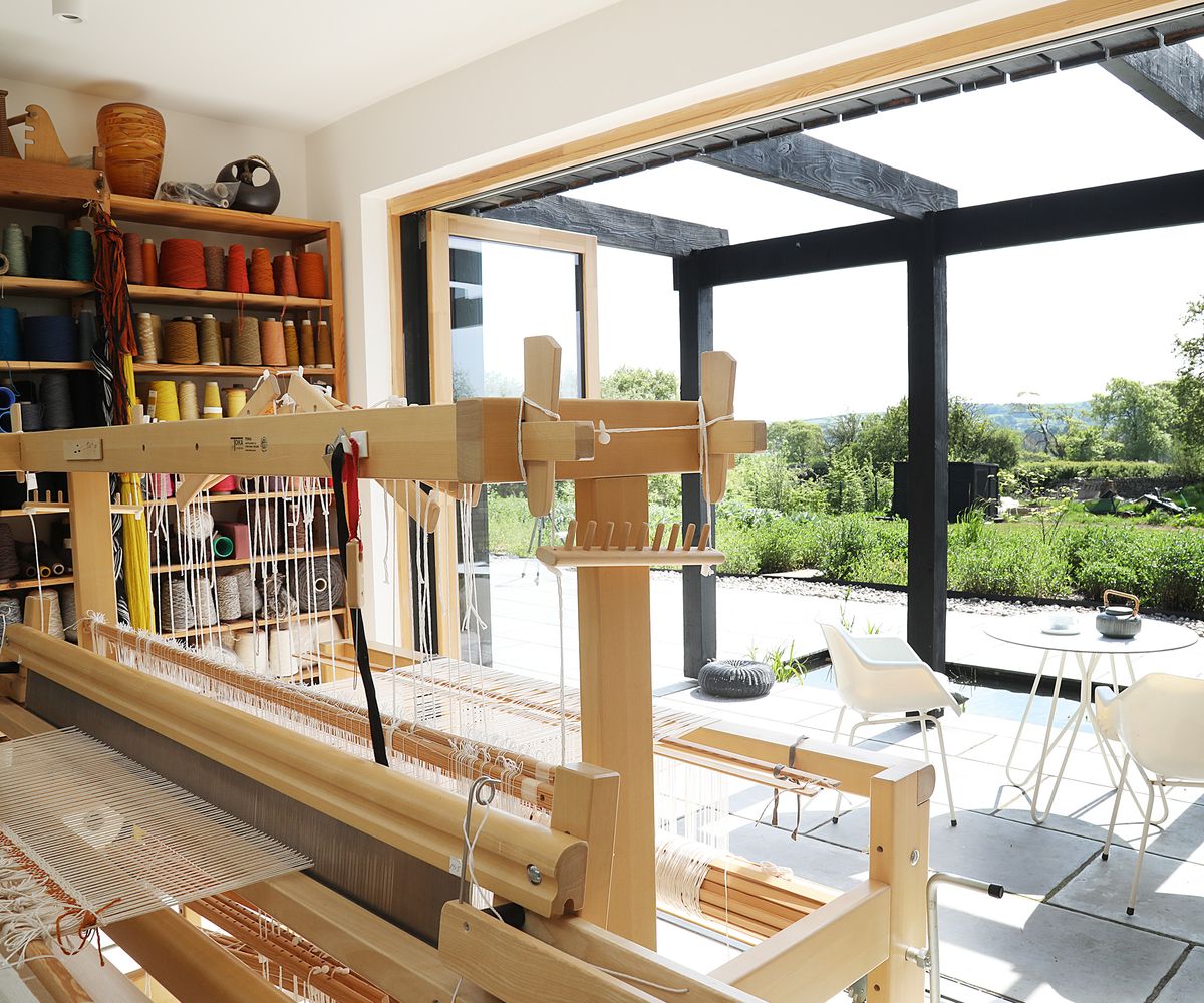 The view out from a home weaving studio with bifold doors fully open and looking out to a garden