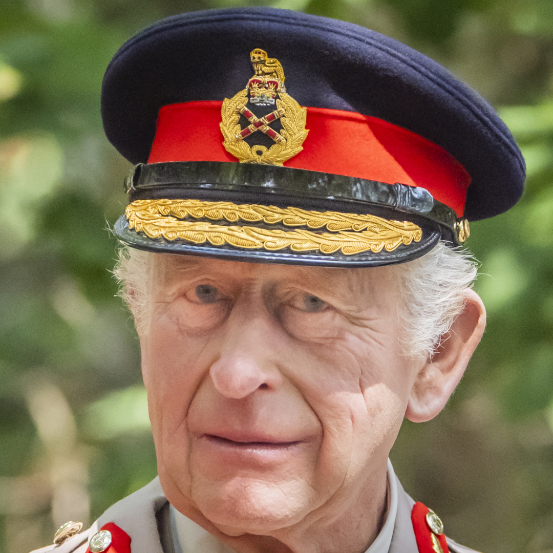 King Charles wearing a military uniform standing in front of a tree