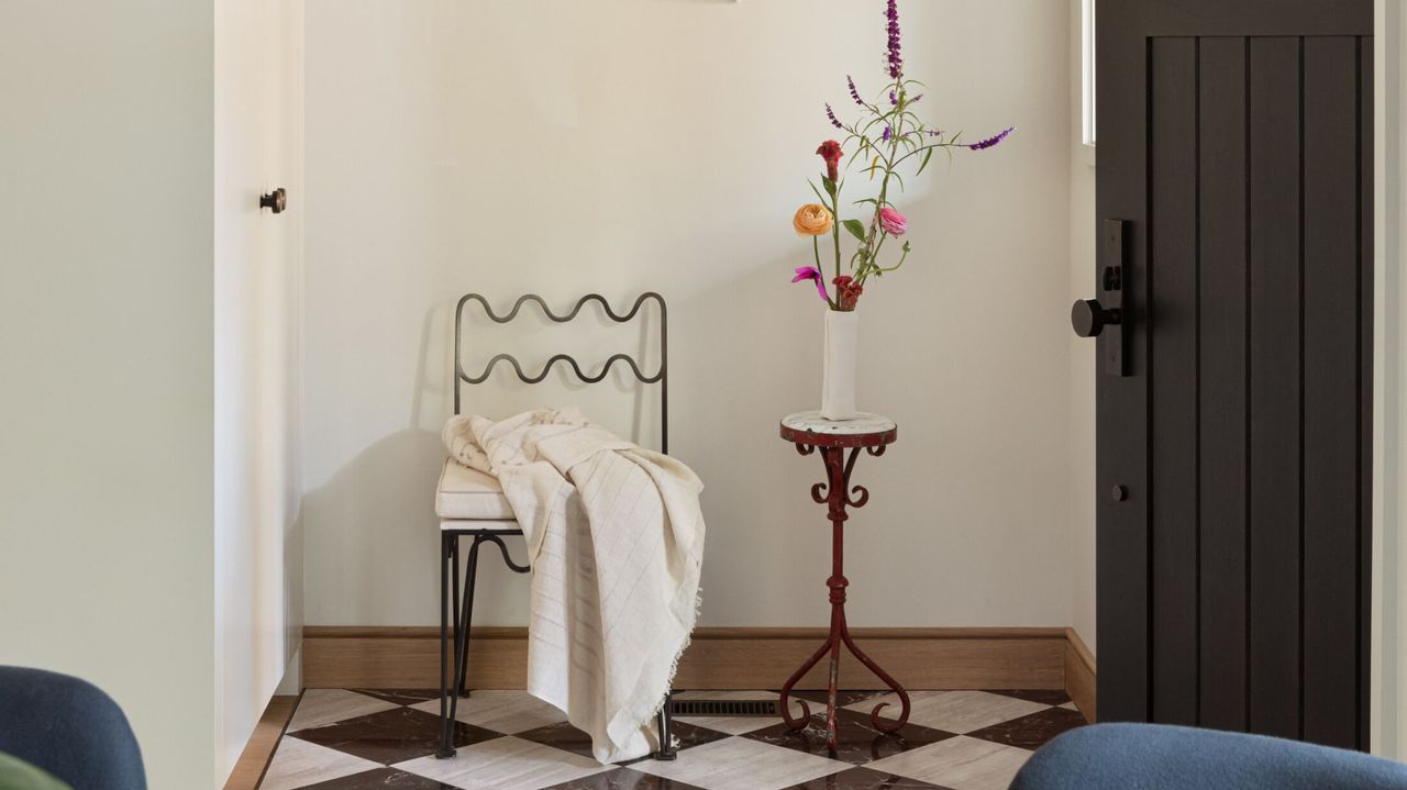 entryway with black door, off-white walls, checked floors and one chair