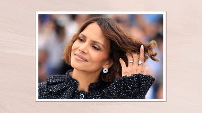 Halle Berry is pictured wearing a black and white top and flicking her hair with her hand (which features a sheer pink manicure) whilst posing during a photocall at the 78th edition of the Cannes Film Festival in Cannes, southern France, on May 13, 2025/ in a pastel pink template