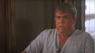 John Candy sitting at a table looking disturbed in Summer Rental.