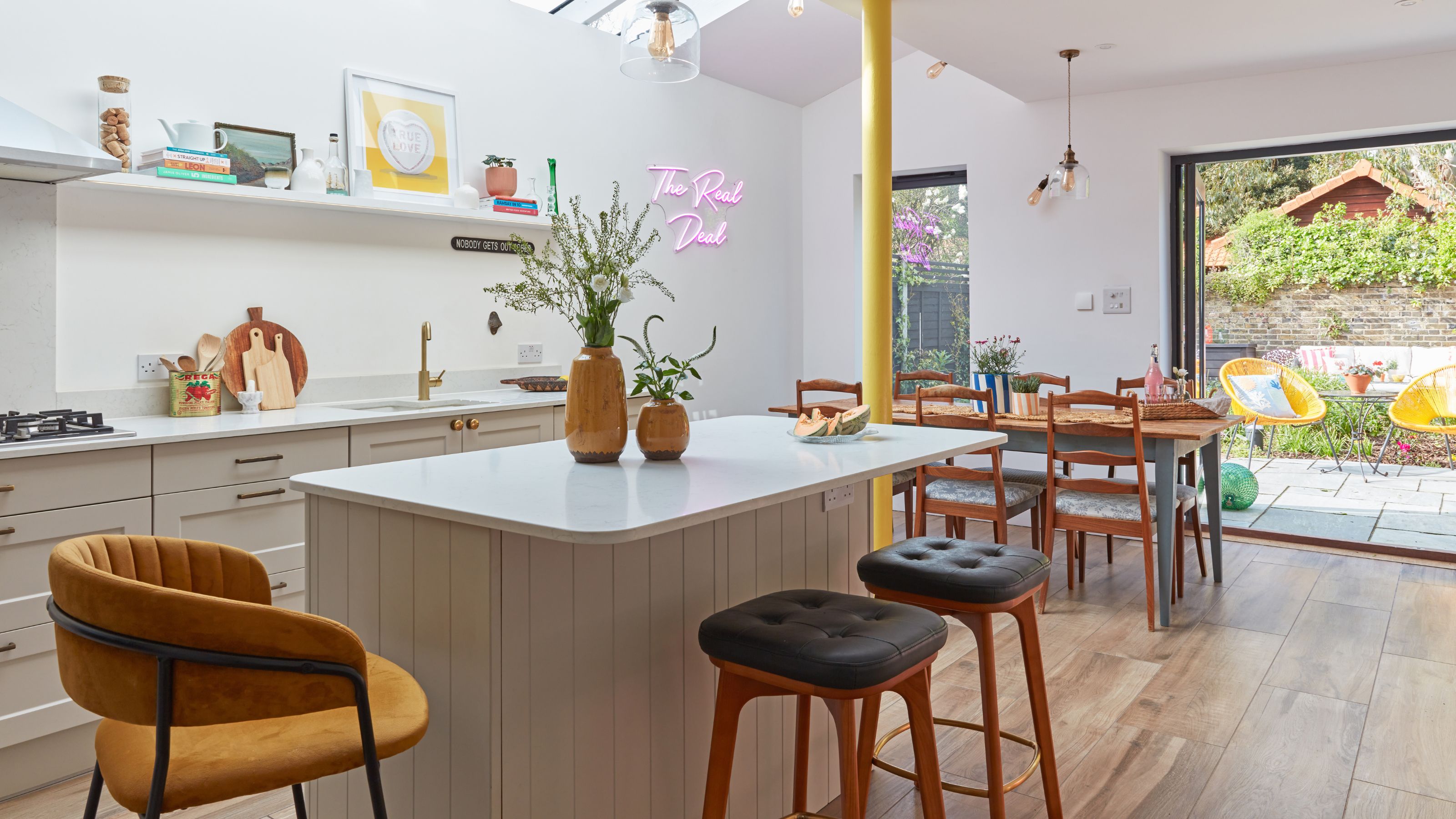 Large kitchen diner with doors out into the garden, and a breakfast bar island with stools around it
