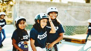 Laughing young female skateboarders hanging out together during summer camp