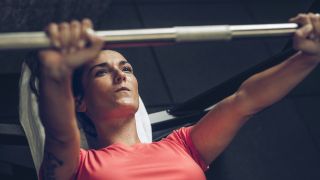 Woman performs close-grip bench press with barbell