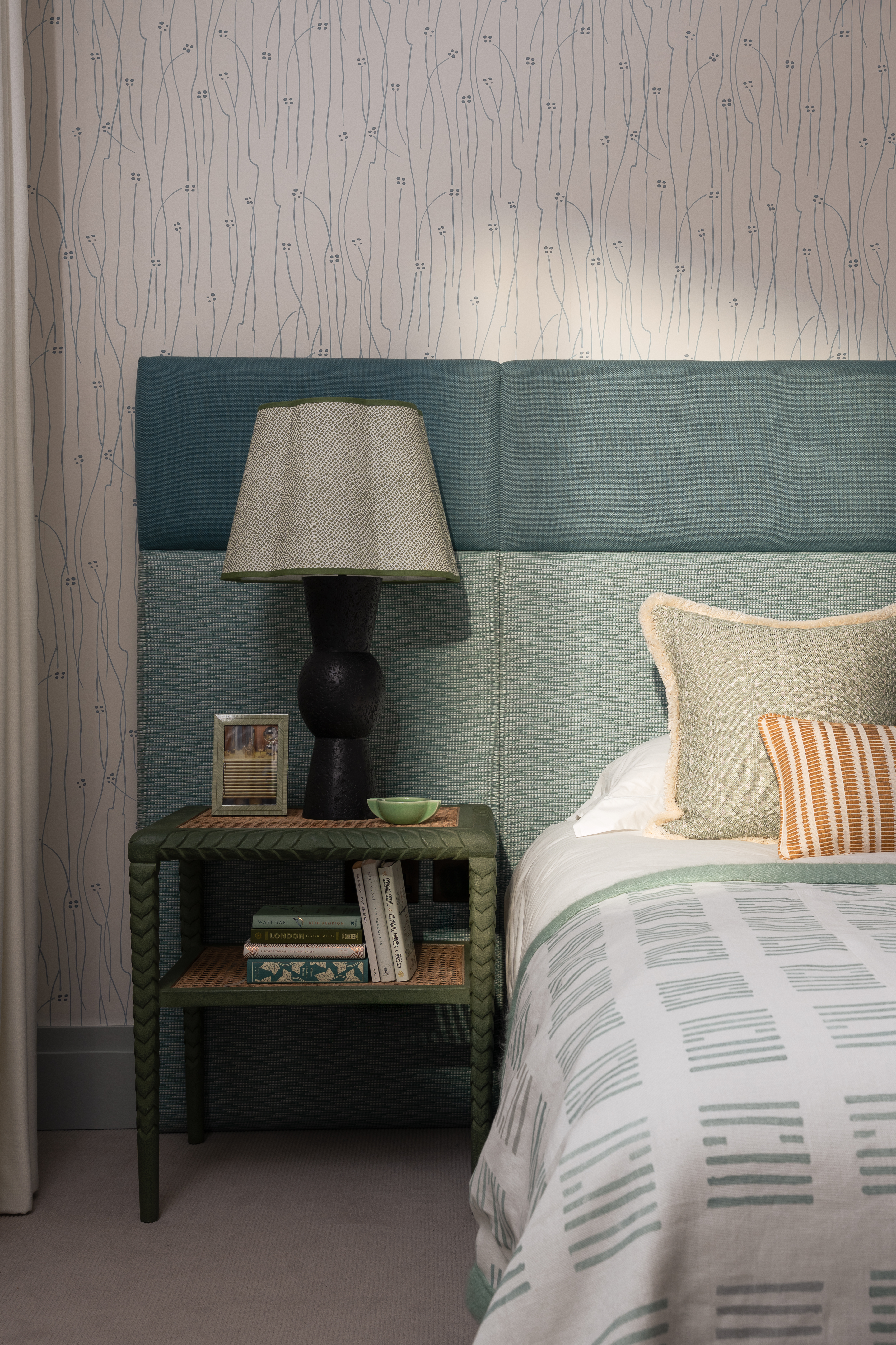 bedroom with blue headboard, a lamp, and a green side table in front