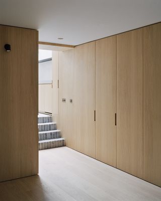 Minimalist cabinetry next to stairs at Islington House by McLaren Excell