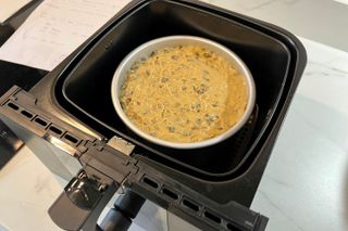 Cake tin with cake mixture in an air fryer basket/drawer