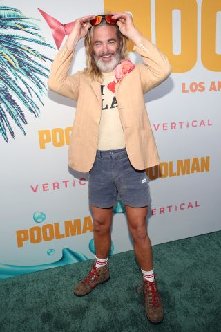 Chris Pine wearing hiking boots, shorts, a T-Shirt that says "I heart LA," a blazer and sunglasses at the premiere of Poolman.