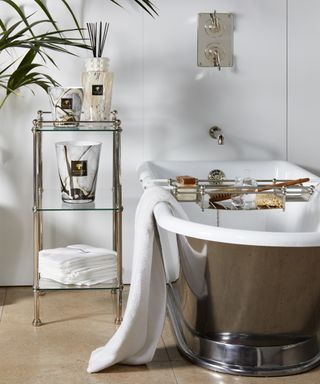 A bathroom with a freestanding metal tub, accessory stand and a bath rack