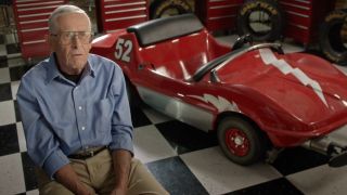 Bob Gurr sitting with an Autopia car in The Imagineering Story