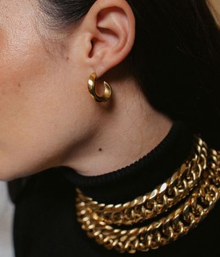 model wears chunky gold necklace and earring