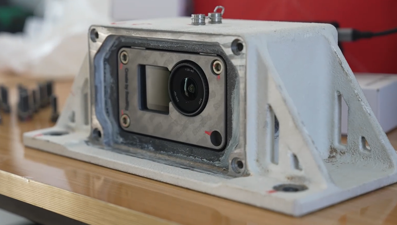 Osmo Action 6 action camera in a metal housing designed to attach it to the side of a rocket