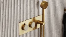 brass handheld shower head with fluted concrete wall panelling