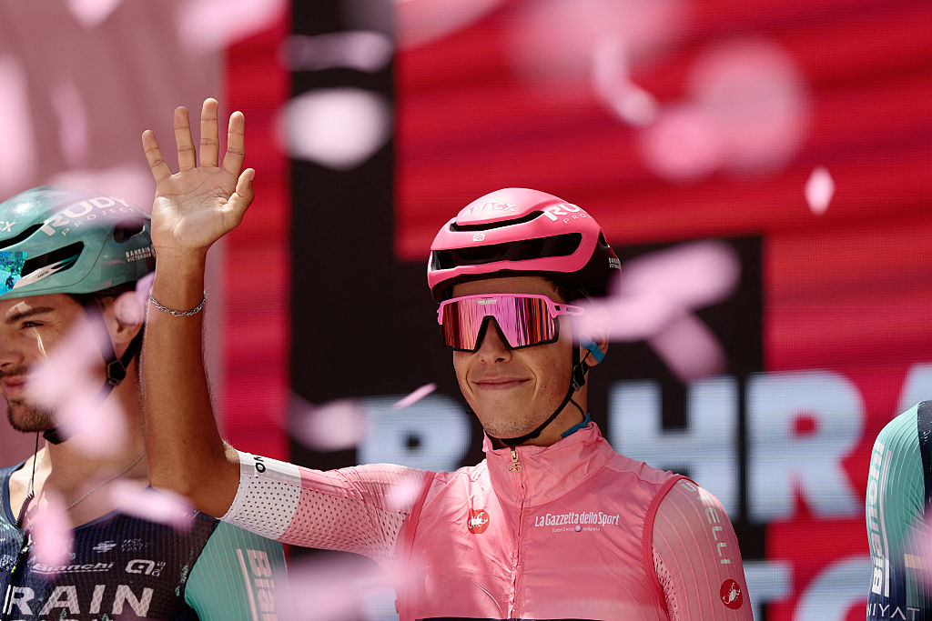 Bahrain - Victorious Portuguese rider Afonso Eulalio, wearing the overall leader's pink jersey (Maglia Rosa), waves on the signature podium before the 8th stage of the Giro d'Italia 2026 - Tour of Italy cycling race between Chieti and Fermo, central Italy on May 16, 2026. (Photo by Luca Bettini / AFP)