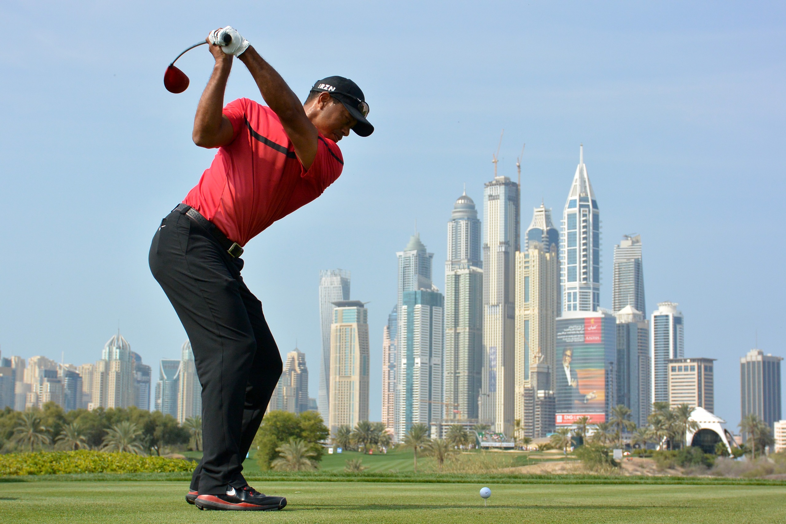 Tiger Woods hits a shot with the Dubai skyline in the background
