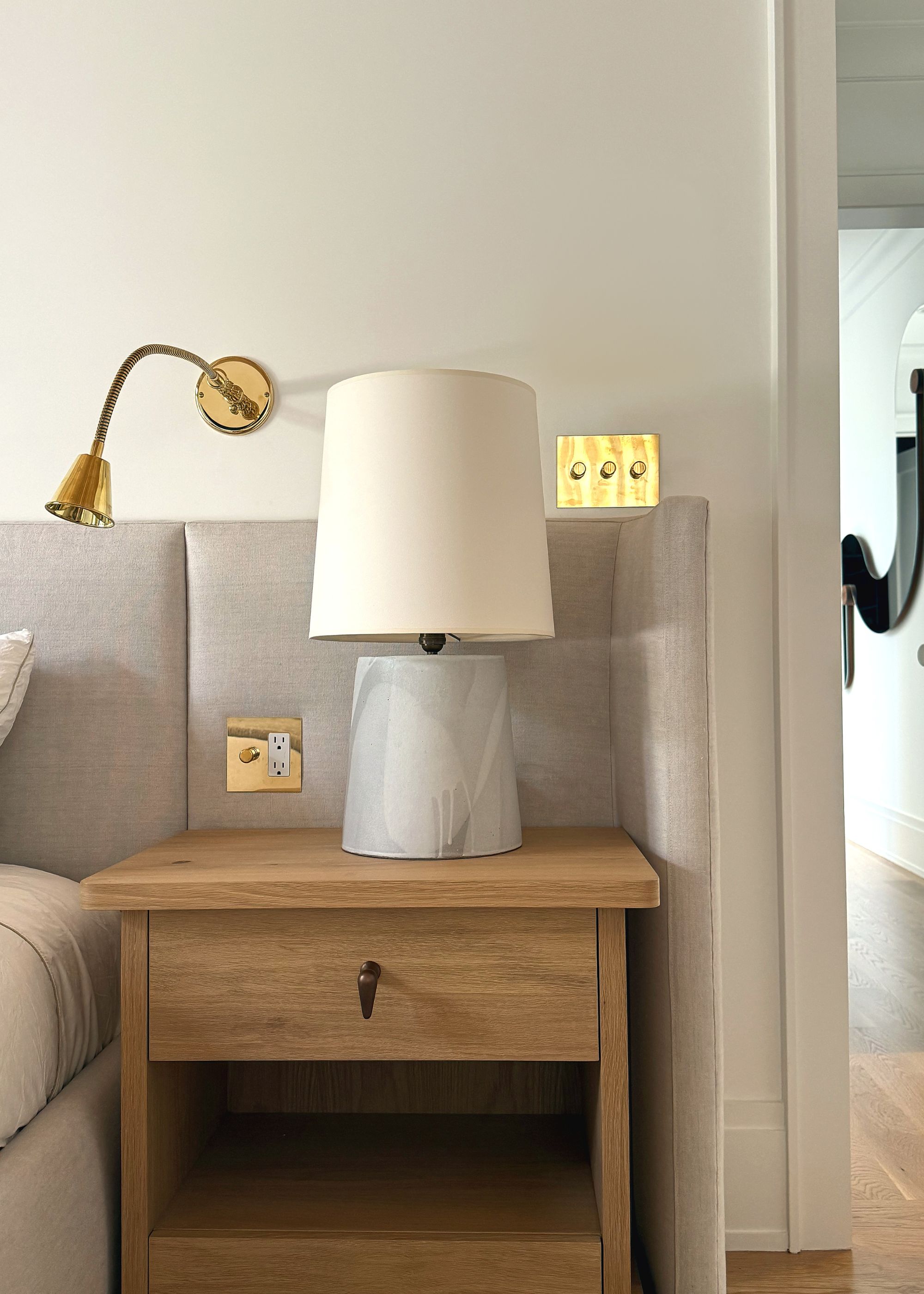 bedside table with wall light, table lamp and brass light switches