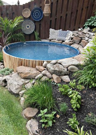 Sloped backyard ideas with a round water feature surrounded by a rockery.