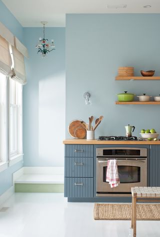 kitchen in a colour scheme of blues with wood worktops, shelves and accessories