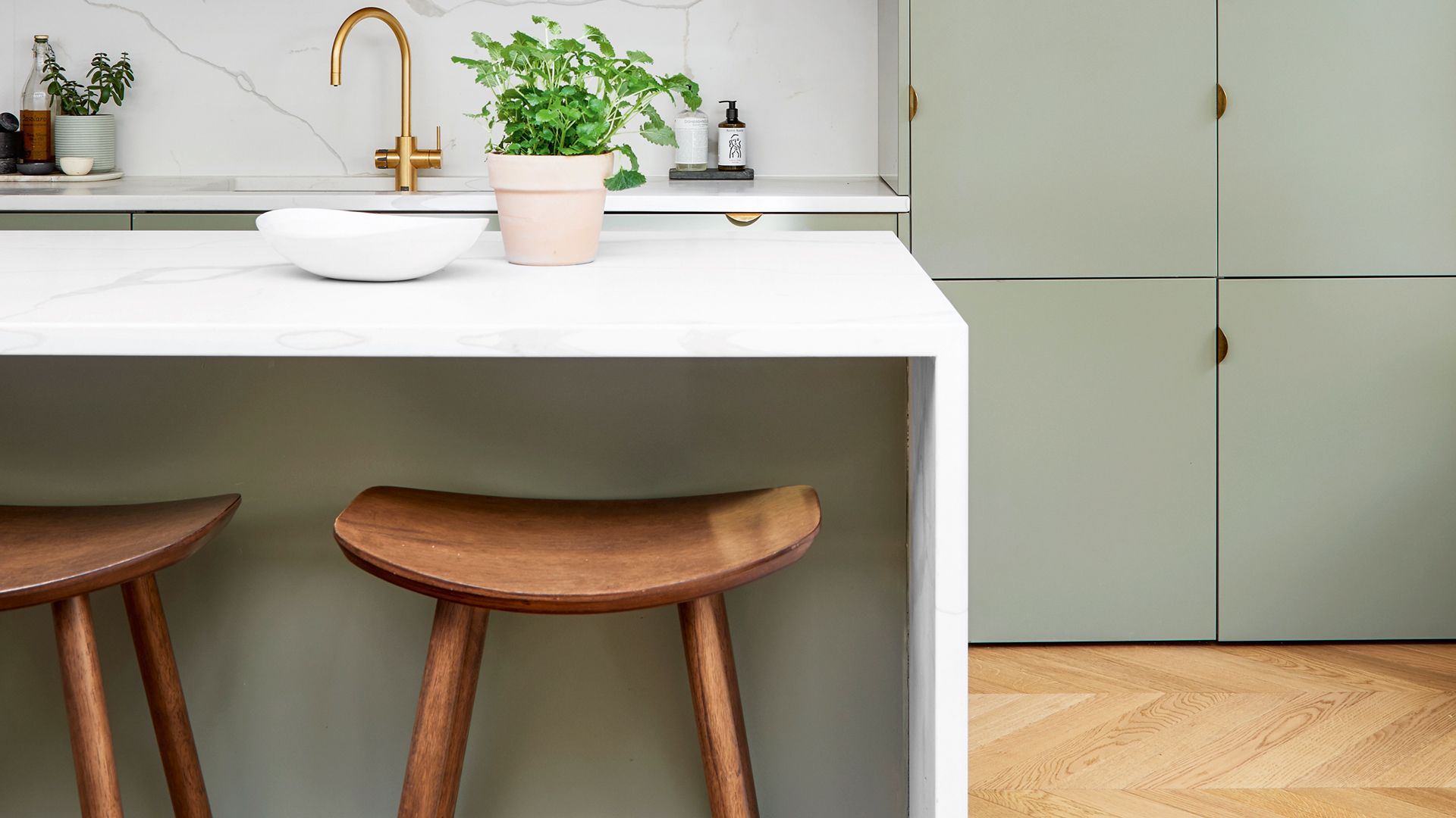 Sage green color trend on kitchen cabinetry complimented by a light oak flooring