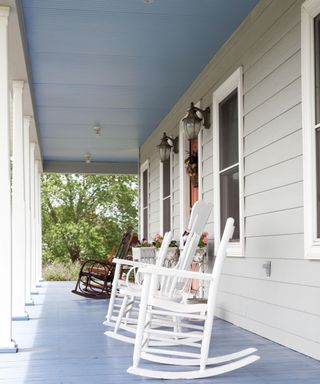 A white porch with white rocking chairs and a light blue ceiling