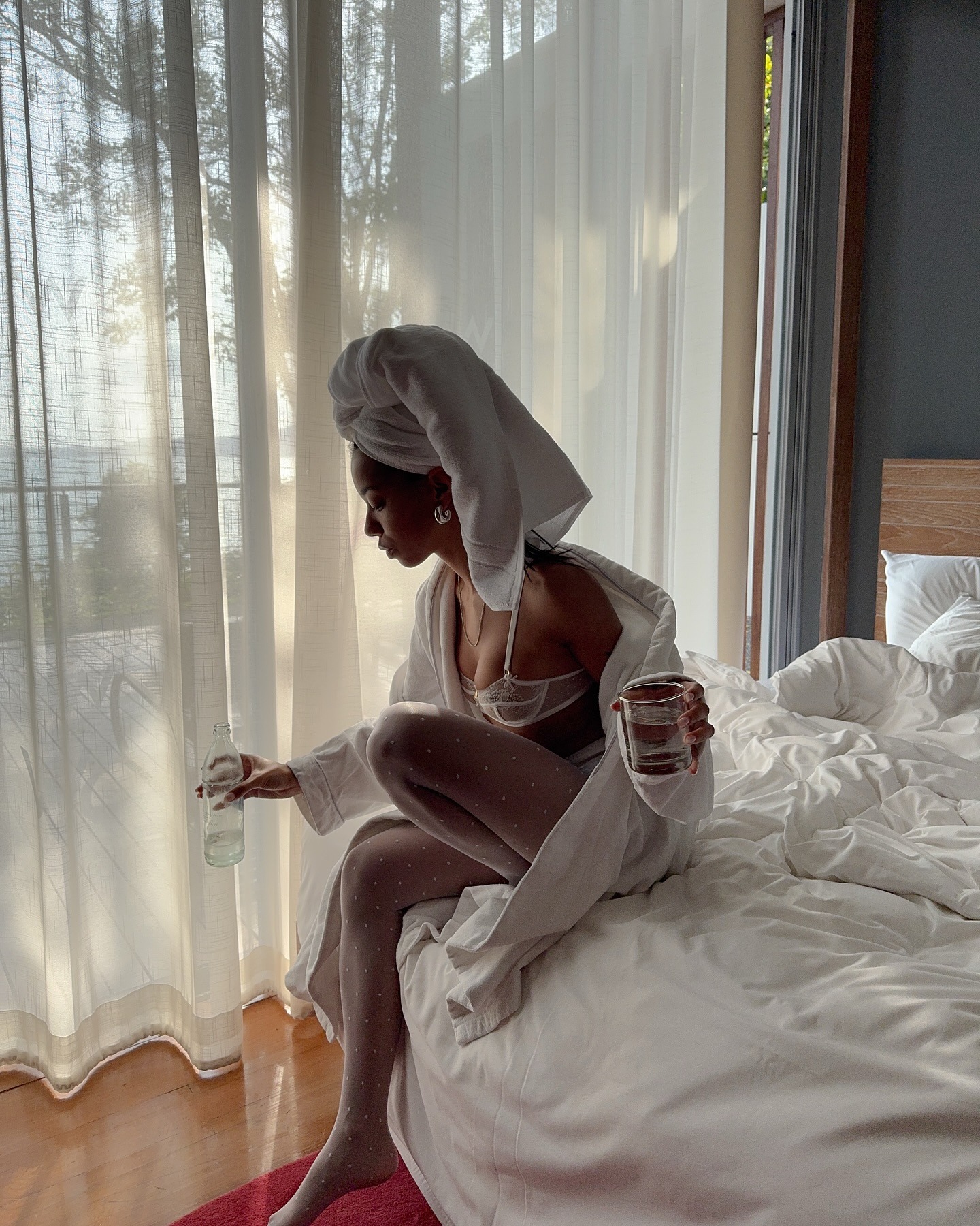 A woman wearing a white robe drinking a glass of water