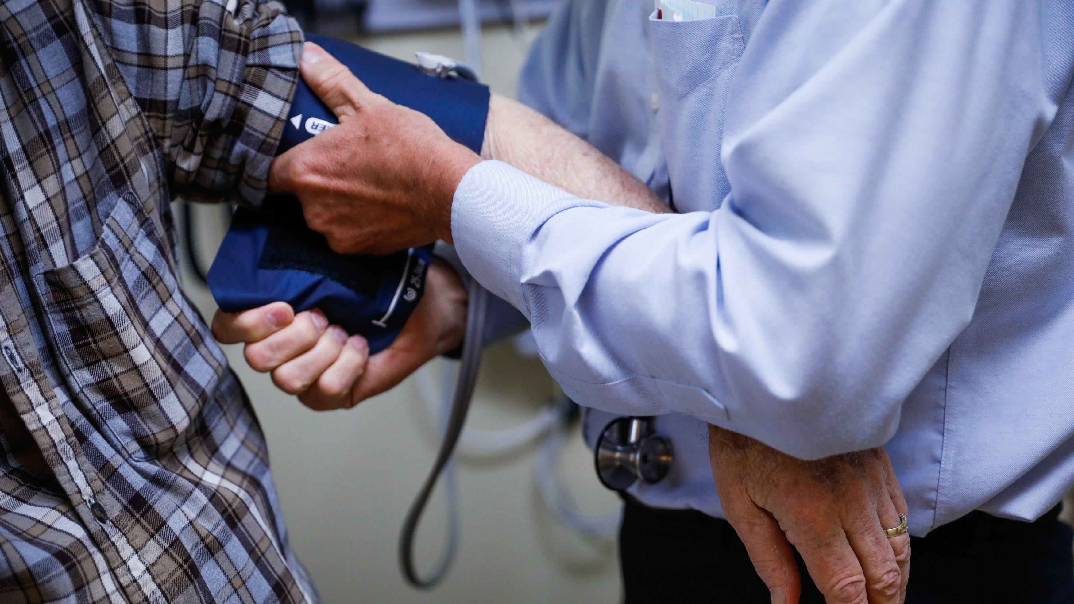 photo of an older man having a blood pressure cuff placed on his arm by a doctor