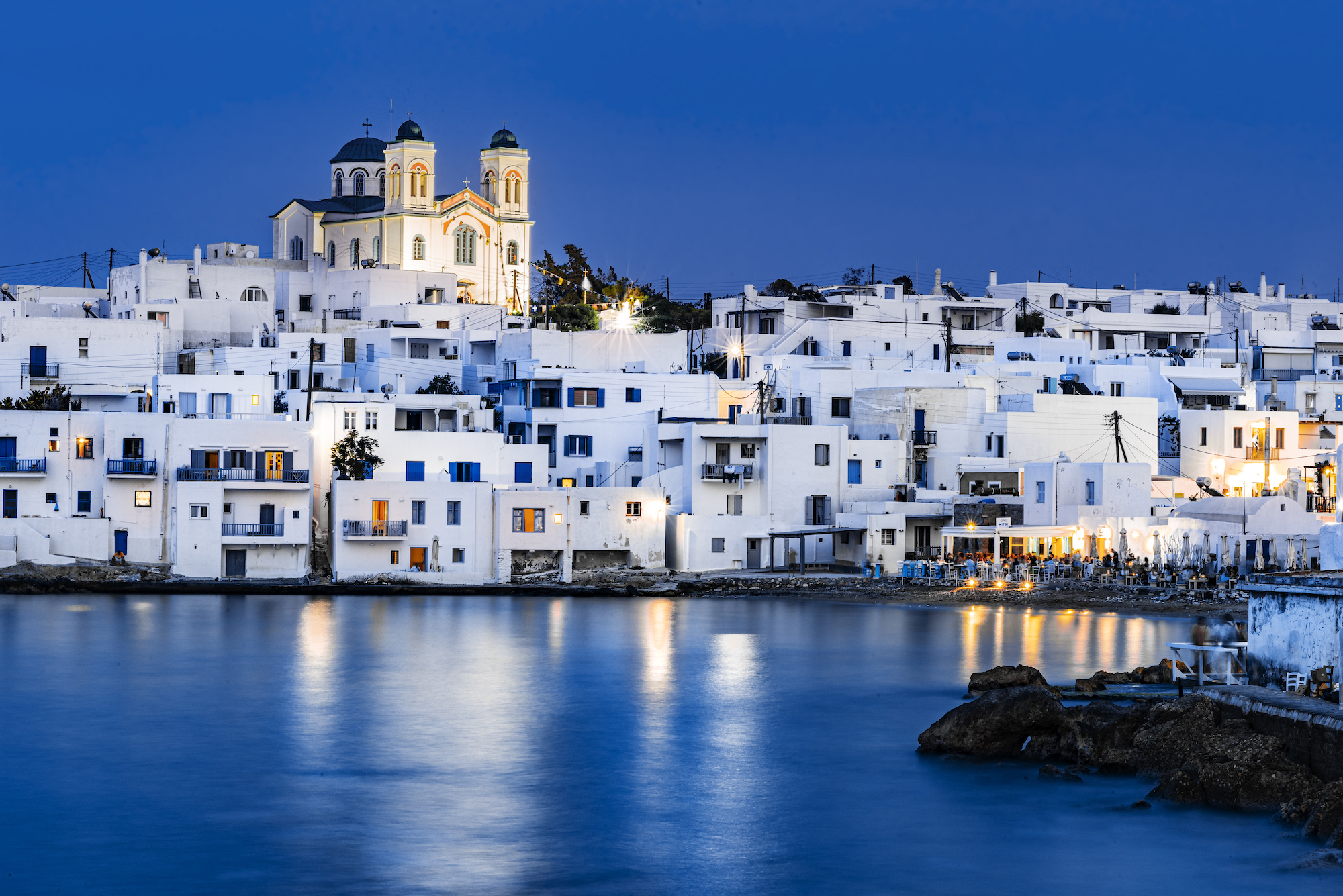 A view of a greek town on the water at night.