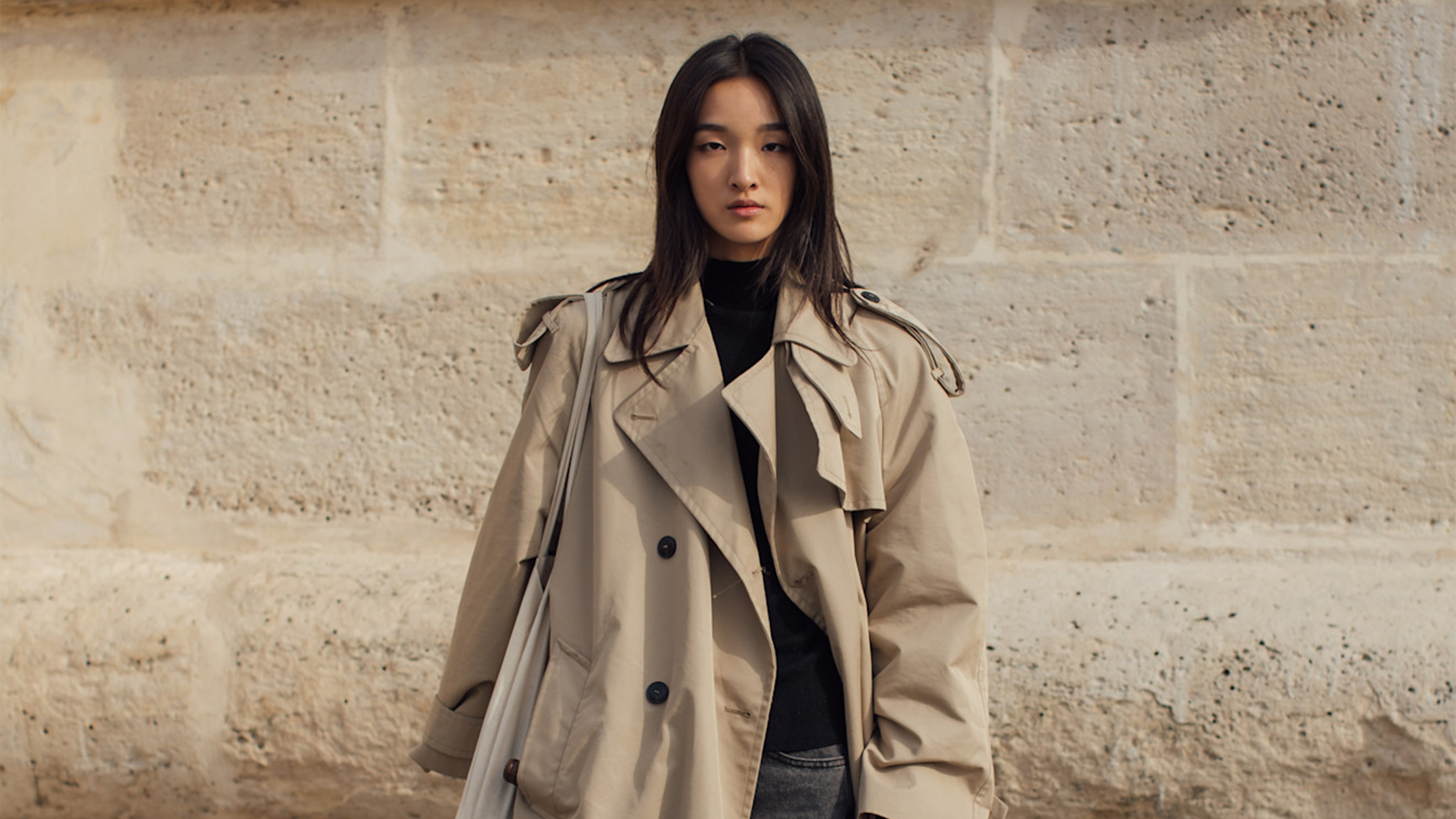 Woman in trench coat, black sweater, black jeans, and boots at Paris SS26 Fashion Week.