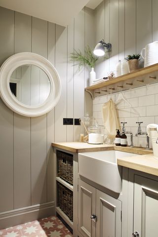Utility room in basement with patterned floor tiles and neutral decor