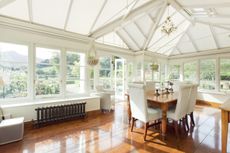 sunroom with dining table and mahogany style flooring white paint