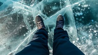 Man's feet standing on frozen lake