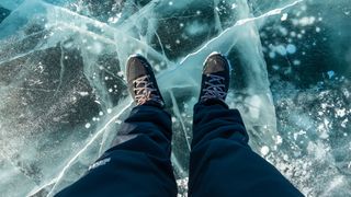 Man&#039;s feet standing on frozen lake