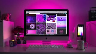 桌面上的一台Mac电脑，以粉色灯光为背景显示网站