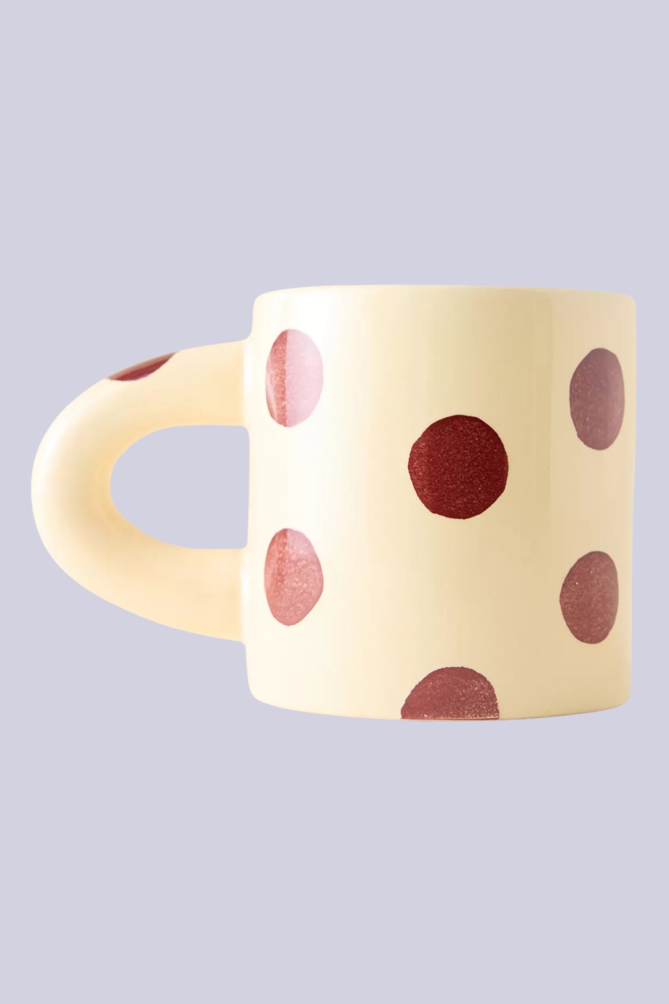 A cream chubby ceramic mug with brown polka dots