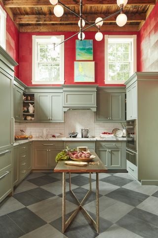 A kitchen with sage green cabinets and red walls