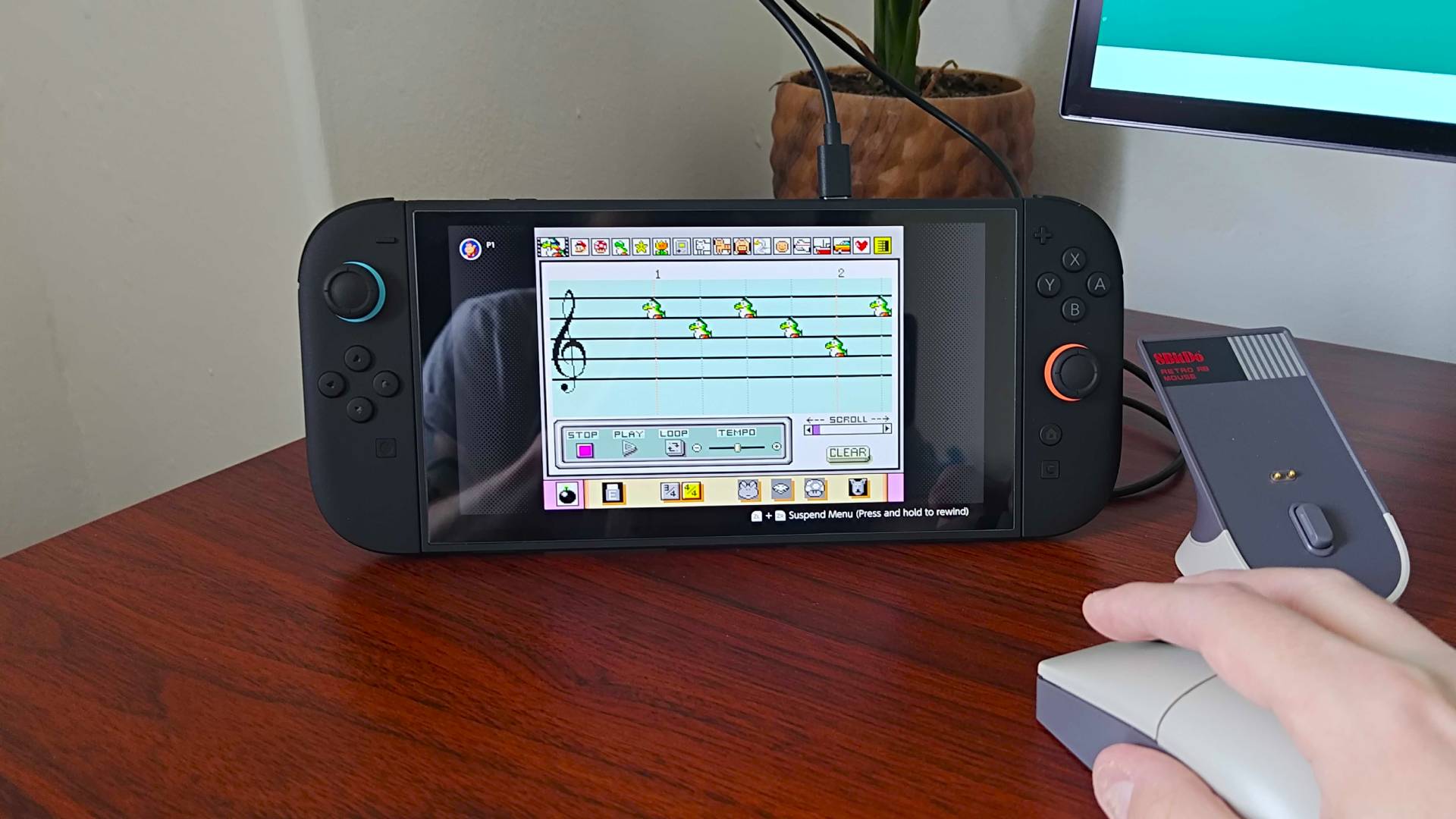 Hand using 8Bitdo Retro R8 to play Mario Paint Composer mode on Switch 2.