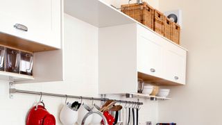 white kitchen cabinets with baskets on top as a budget kitchen storage idea