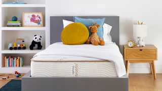 The Saatva Youth Mattress, the best option for kids aged 3-12, shown in a kids room with pillows and a cuddly toy