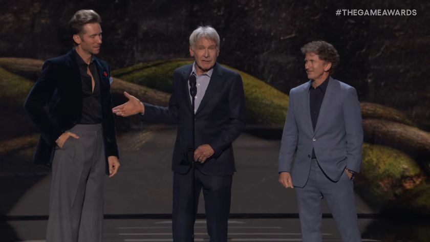 Harrison Ford standing on stage between Troy Baker and Todd Howard while pointing to Howard