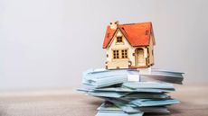 Model of a house sitting on bundles of cash