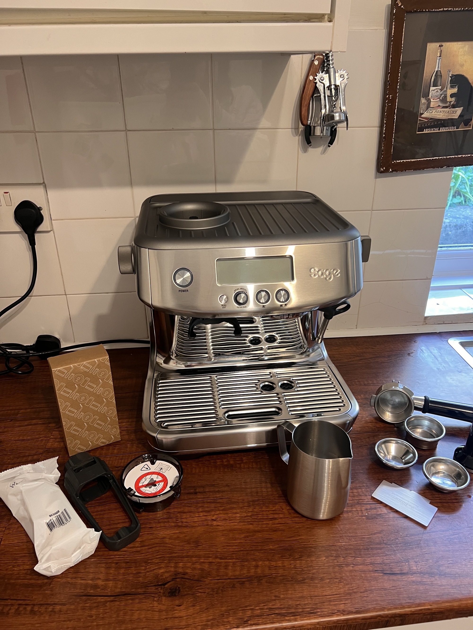 a silver sage barista pro machine on a wooden countertop with accessories next to it.
