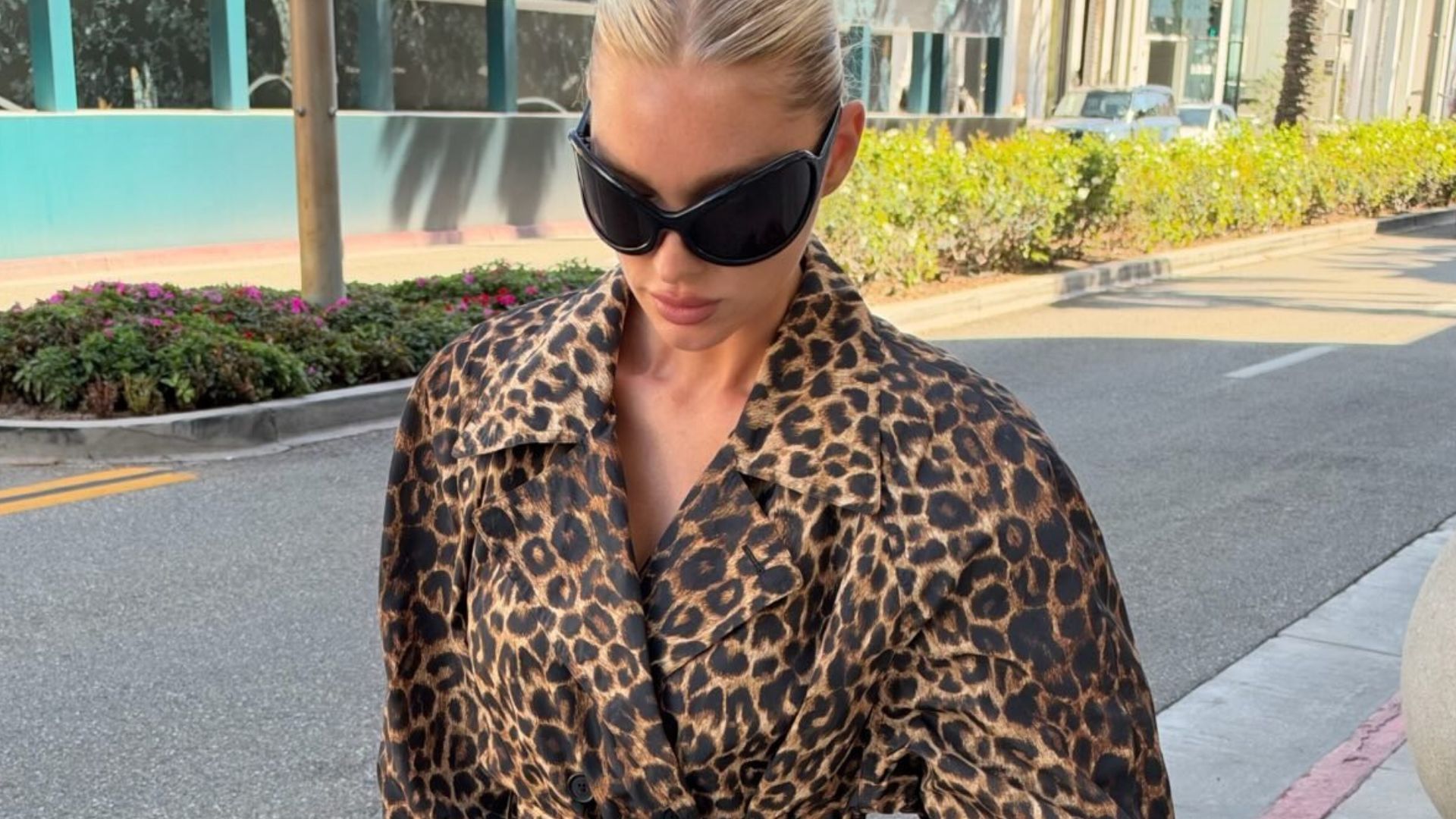 Elsa Hosk walks down the street wearing a leopard print trench coat with relaxed, slightly distressed jeans and navy satin mules.