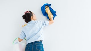 Woman cleaning a wall with blue cloth