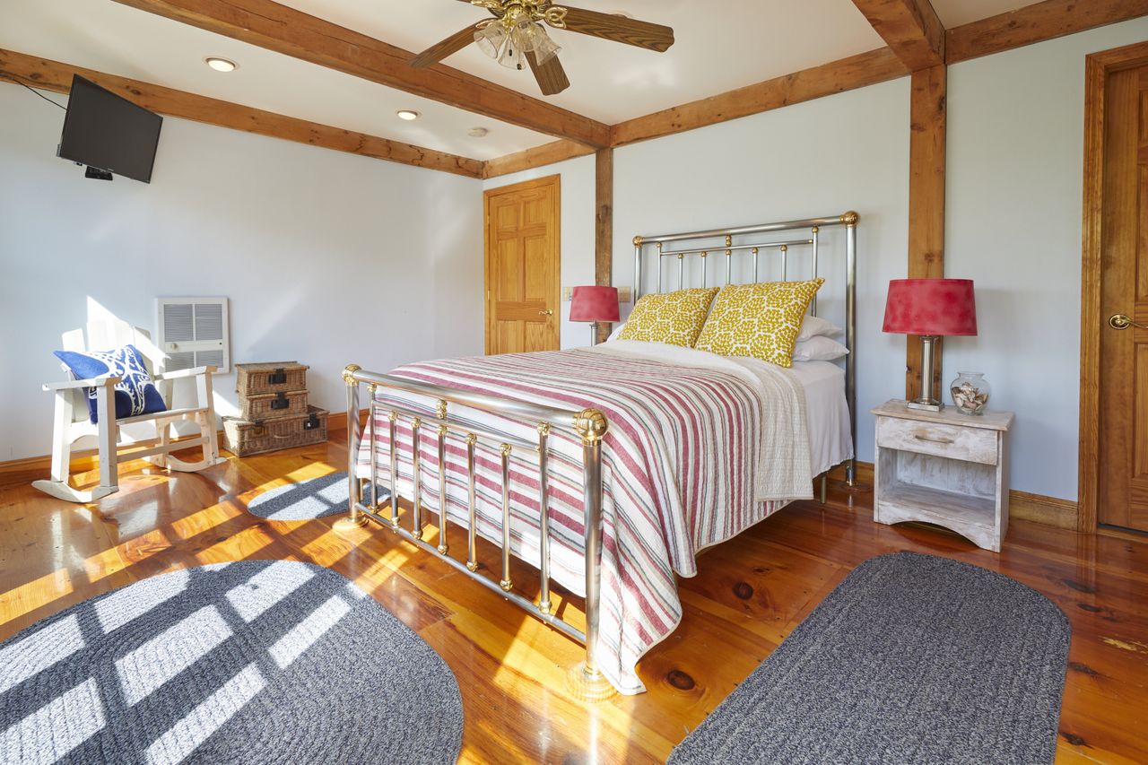 A dated bedroom with wooden floors and beams