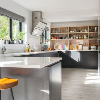 yellow bar stool next to grey kitchen cupboards in spacious kitchen with wooden floor