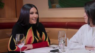 Kim and Kourtney sitting at a restaurant in The Kardashians season 2