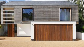 contemporary house with horizontal timber cladding and fumed oak garage door and front door and resin driveway