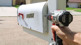 Installing the Ring Mailbox Sensor by drilling a hole in the back of a mailbox with a power drill