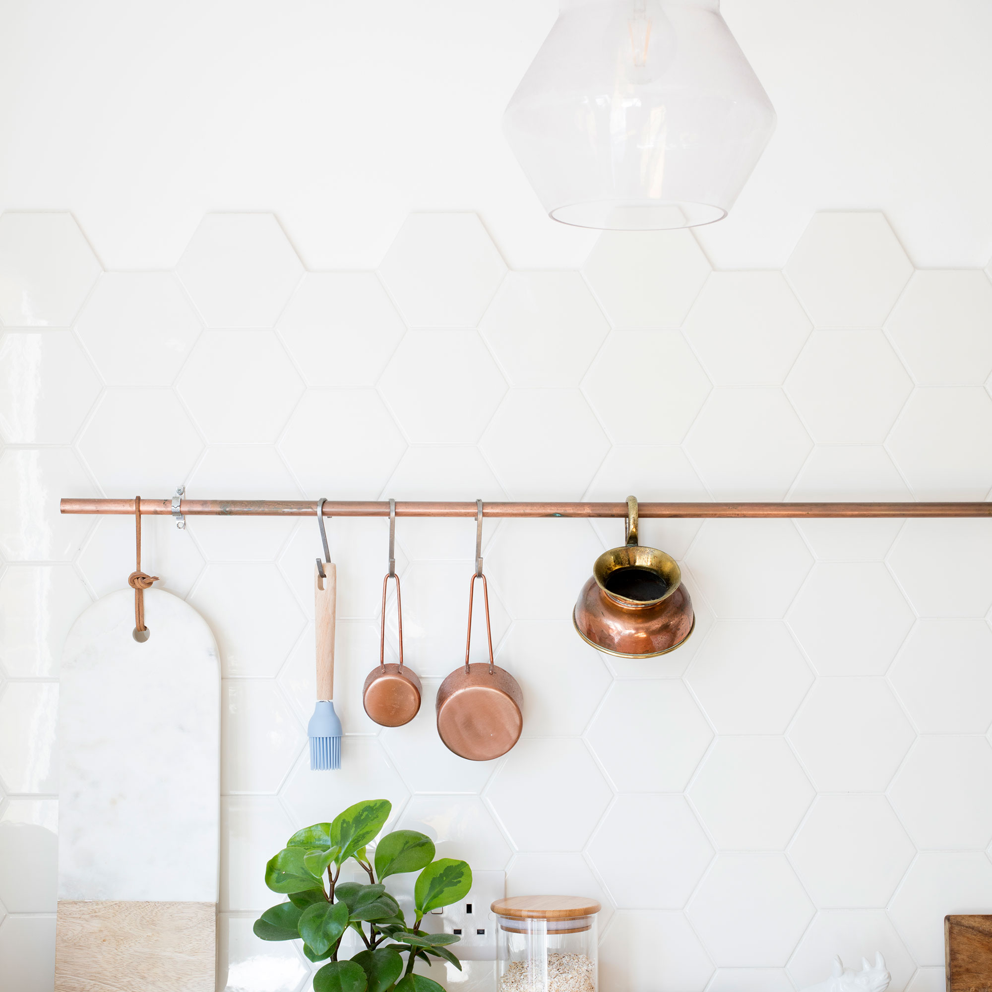 White kitchen with tiled splashback and utensils hanging from pole