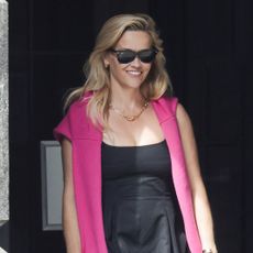 Reese Witherspoon steps out in new york city wearing a little black dress and an elle woods pink sweater with ray ban sunglasses